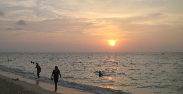 People walking on the beach and swimming in the ocean.